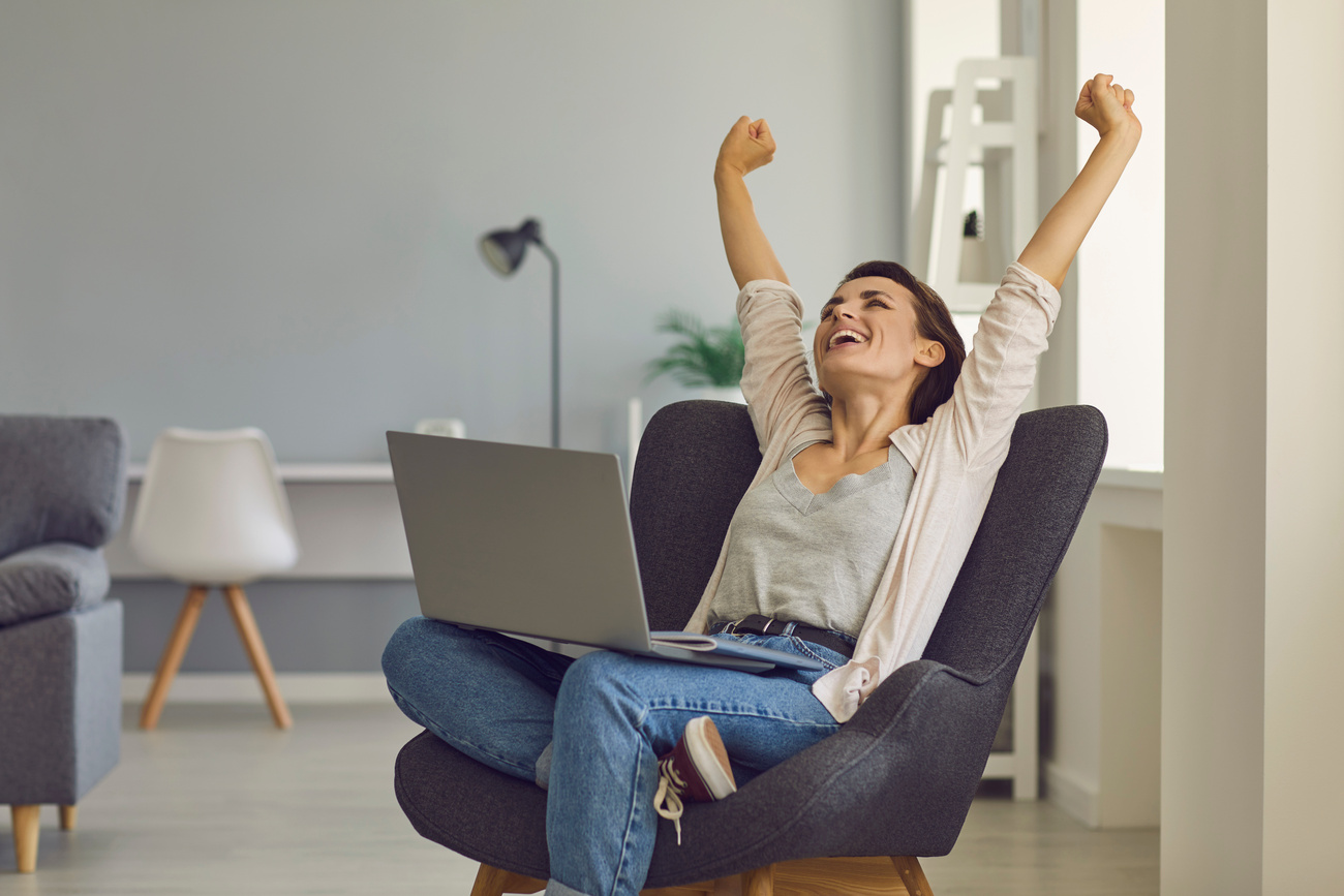 Positive Young Girl with Laptop Stretching in Cozy Armchair after Work. Beautiful Businesswoman Relaxing at Home Office